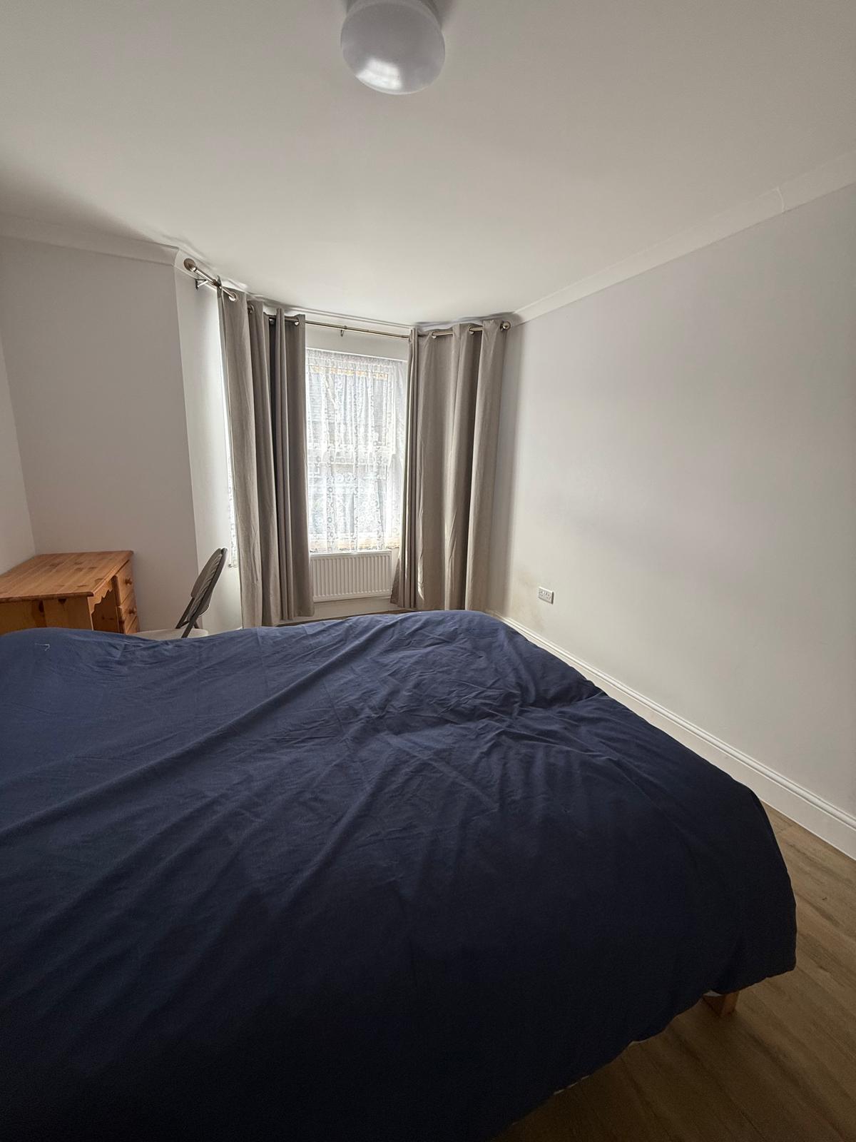 Double bedroom with bay window and neutral curtains